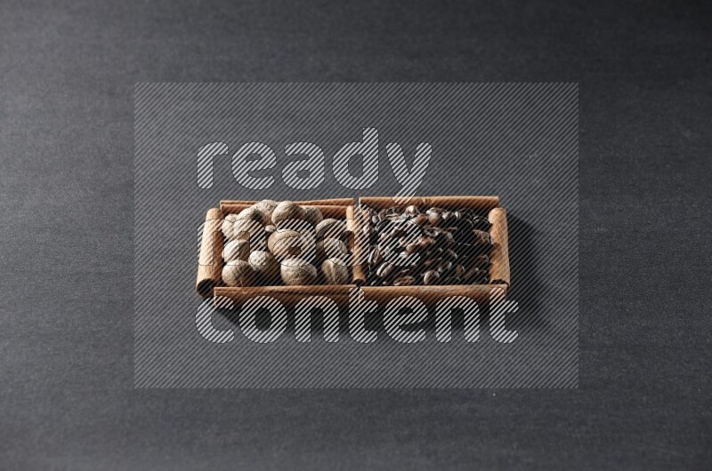 مربعان من أعواد القرفة ممتلئان بحبوب القهوة وجوزة الطيب علي خلفية سوداء