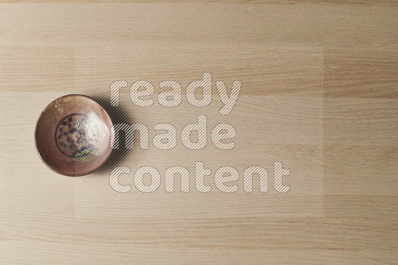 صحن فخاري مزخرف على خلفية خشبية فاتحة