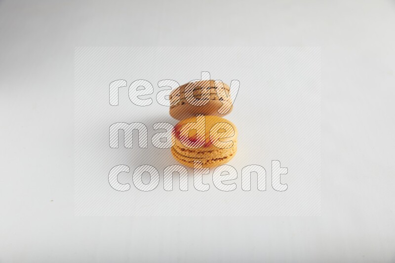45º Shot of of two assorted Brown Irish Cream, and Orange Exotic macarons on white background