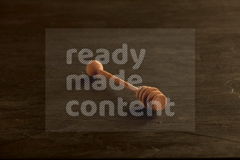 Wooden honey dipper on black slate background