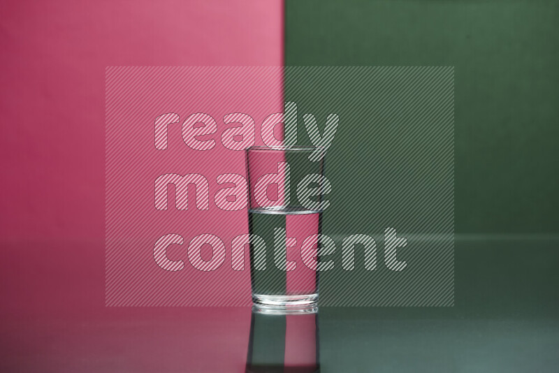 The image features a clear glassware filled with water, set against pink and dark green background