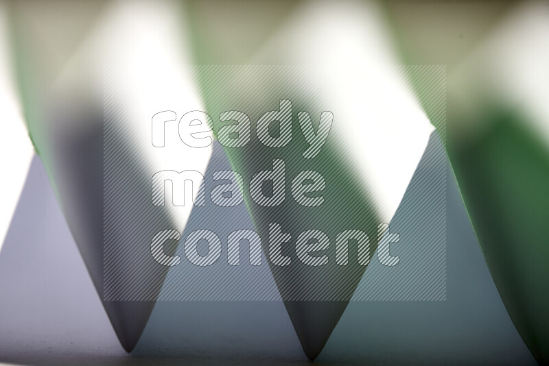 A close-up abstract image showing sharp geometric paper folds in white and green gradients