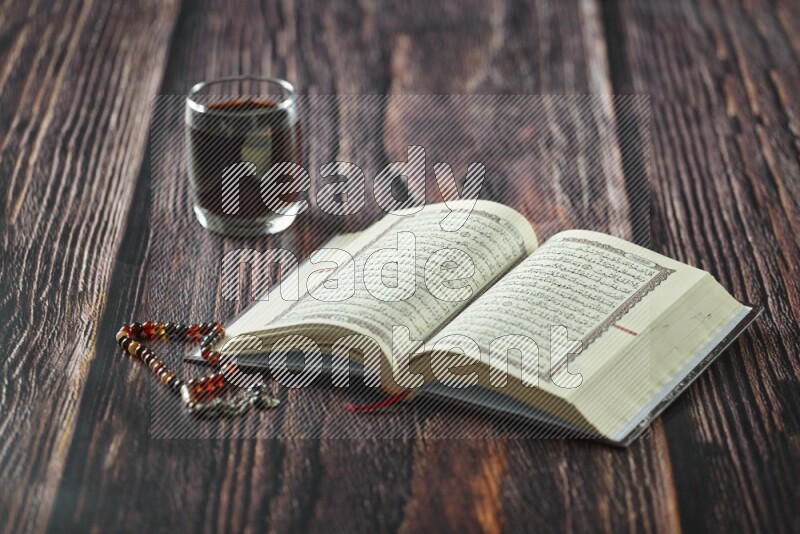 Quran with dates, prayer beads and different drinks all placed on wooden background