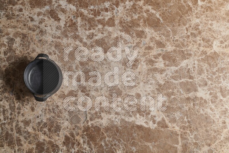 A black pottery bowl on beige marble background