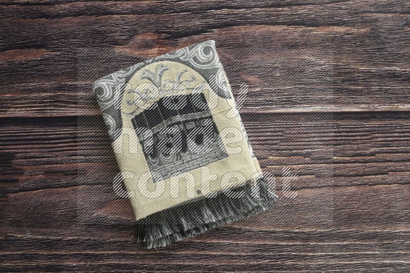 سجادة صلاة مطوية بعناصر مختلفة مثل القرآن الكريم وسبحة الصلاة على خلفية خشبية بنية