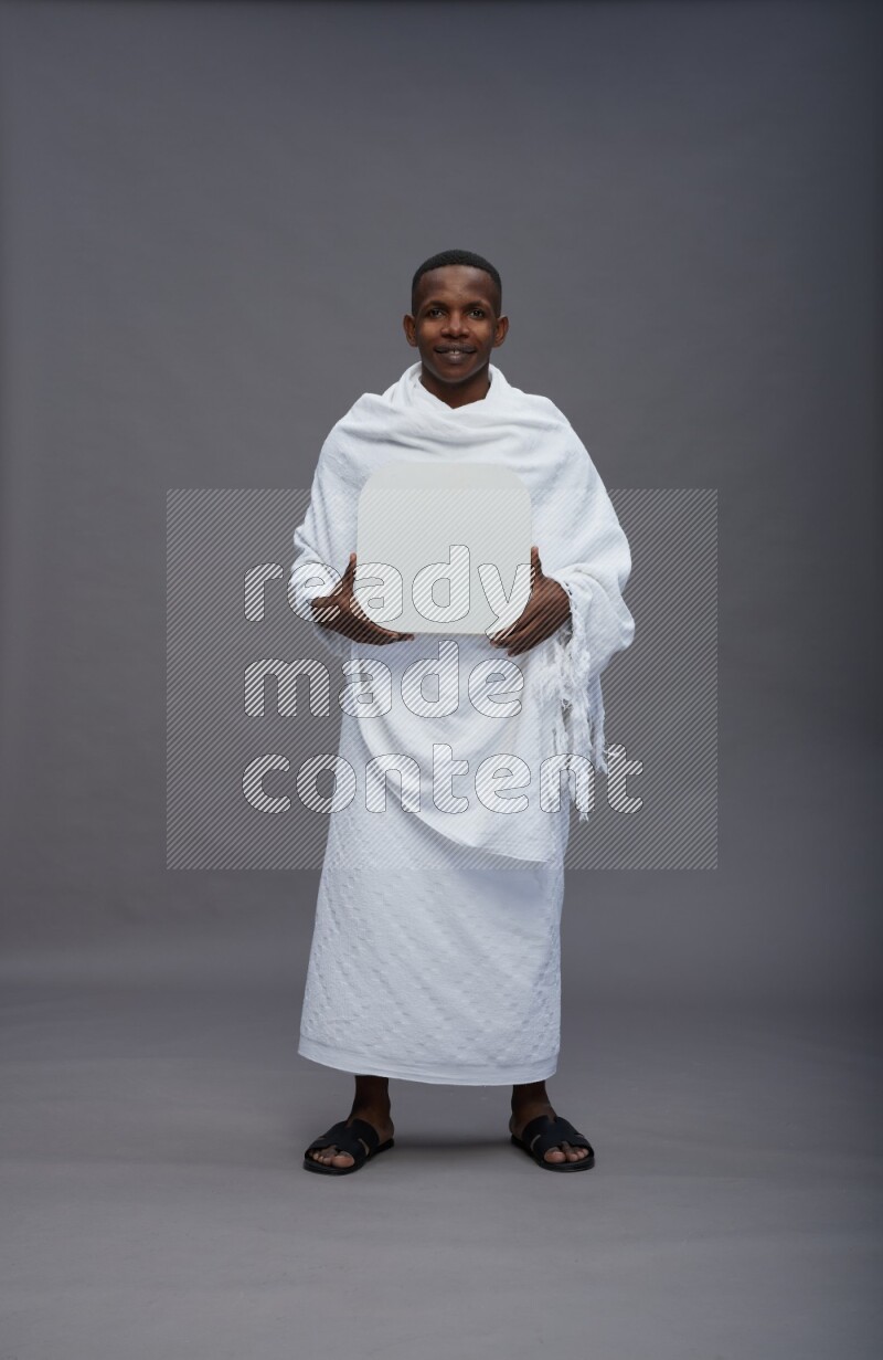 A man wearing Ehram Standing holding social media sign on gray background