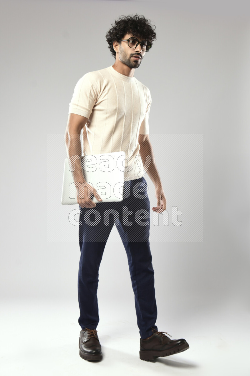 A man wearing casual standing and holding a laptop on white background
