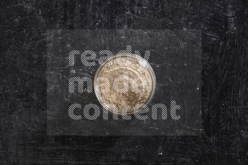 وعاء زجاجي ممتلئ ببودرة الثوم علي خلفية سوداء