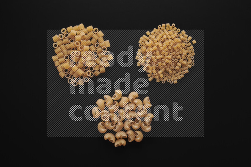 Different pasta types in bunches on black background