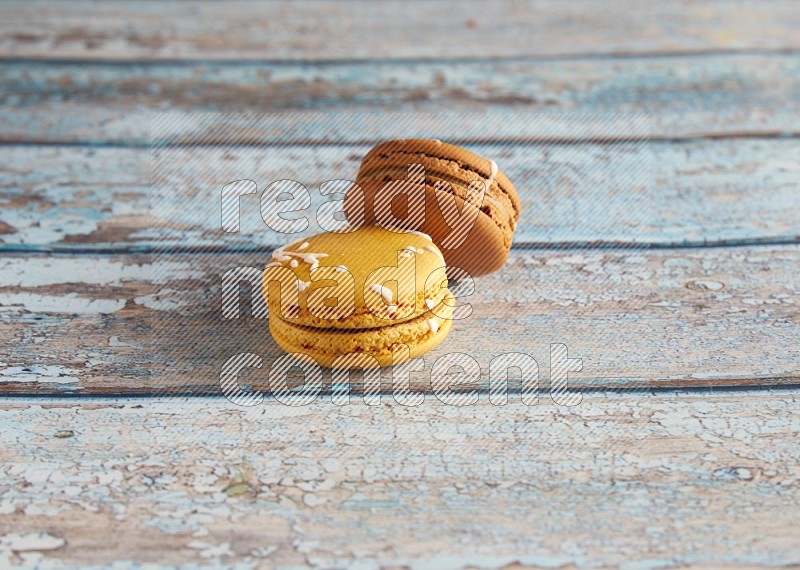 45º Shot of of two assorted Brown Irish Cream, and Yellow Piña Colada macarons on light blue background