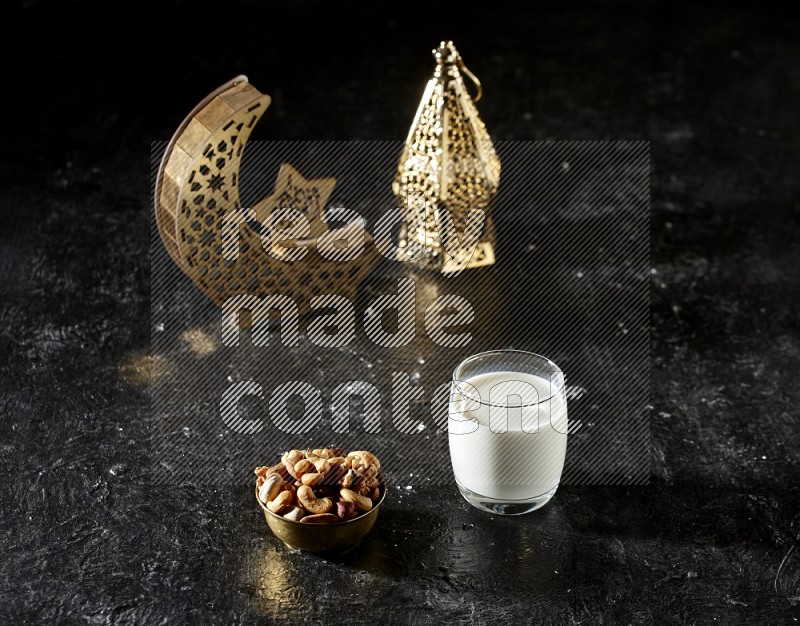 Nuts in a metal bowl with milk beside golden lanterns in a dark setup