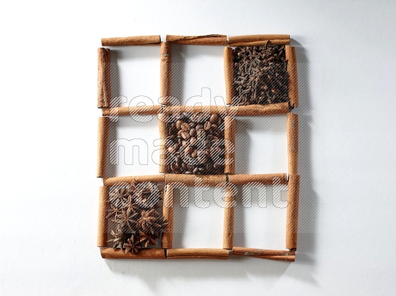 9 squares of cinnamon sticks full of coffee beans in the middle surrounded by dried mint, dried ginger, cardamom, star anise, cinnamon, nutmeg, dried basil and cloves on white flooring
