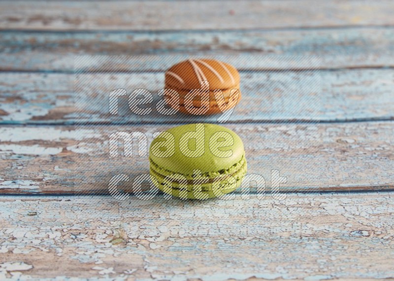 45º Shot of of two assorted Brown Irish Cream, and Green Pistachio macarons  on light blue background