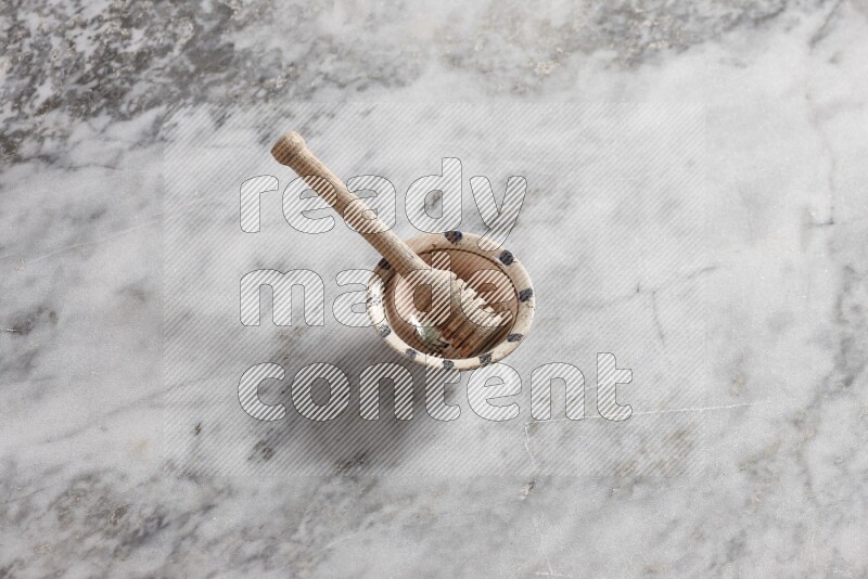 Decorative pottery bowl with wooden honey dipper in it on grey marble background