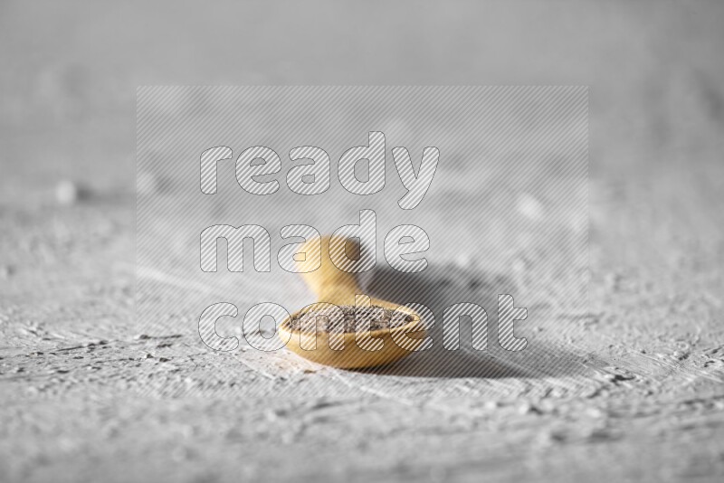 فلفل أسود مطحون في ملعقة خشبية علي خلفية بيضاء