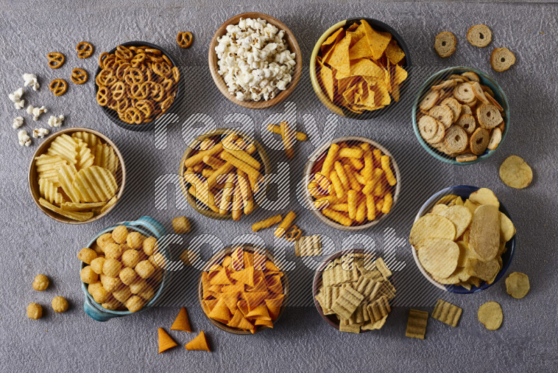 Assorted snacks in pottery bowls on grey background