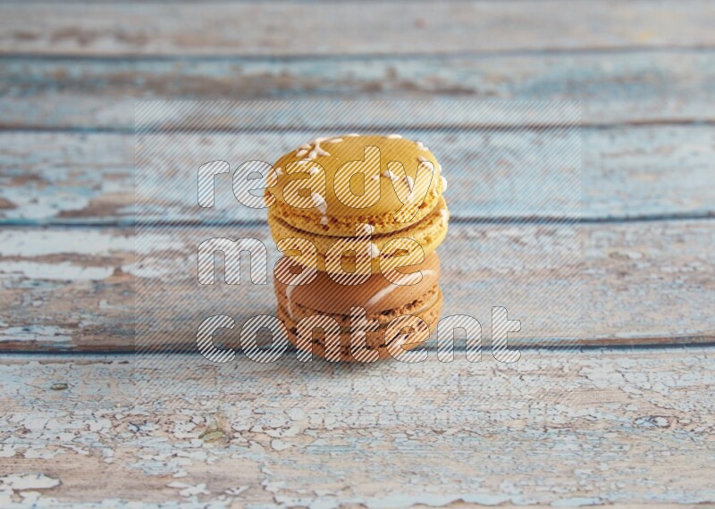 45º Shot of of two assorted Brown Irish Cream, and Yellow Piña Colada macarons on light blue background