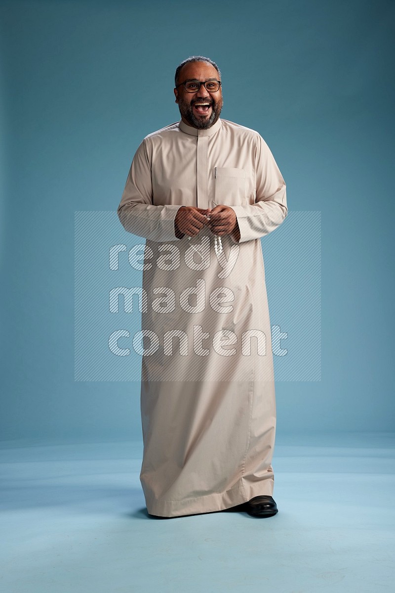 Saudi Man without shimag Standing Interacting with the camera on blue background