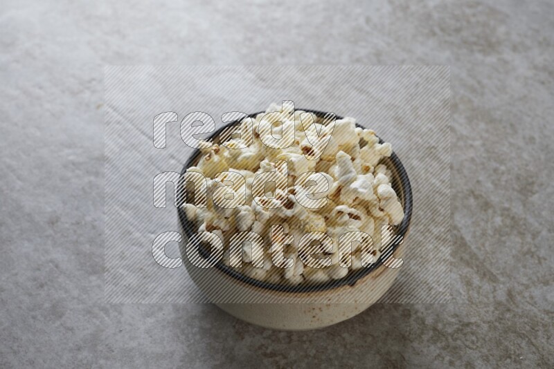 popcorn in multi-colored pottery bowl on a grey textured countertop