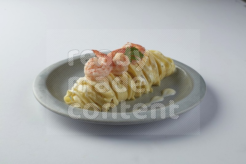 Fettuccini white sauce pasta with shrimp in a white plate on a white background