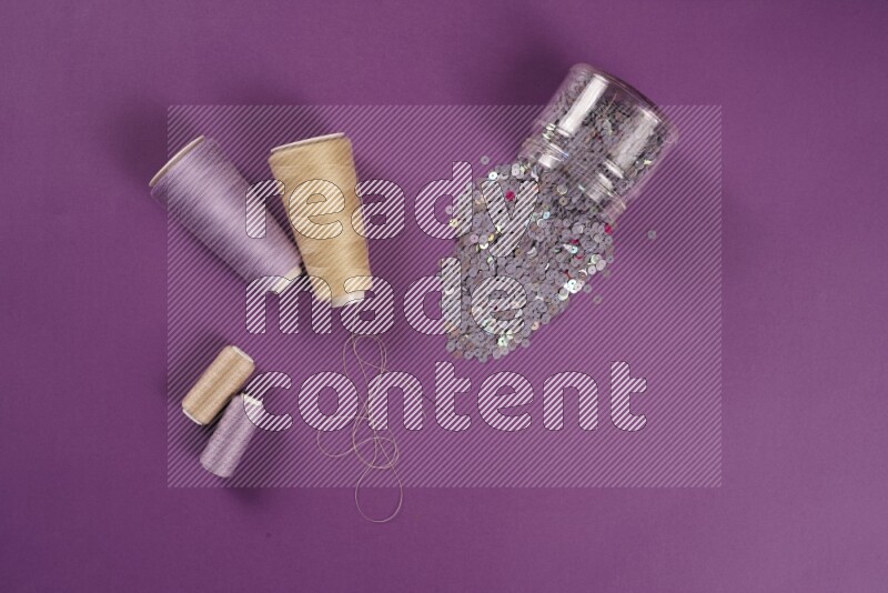 A beige collection of sewing and tailoring tools arranged on a purple background