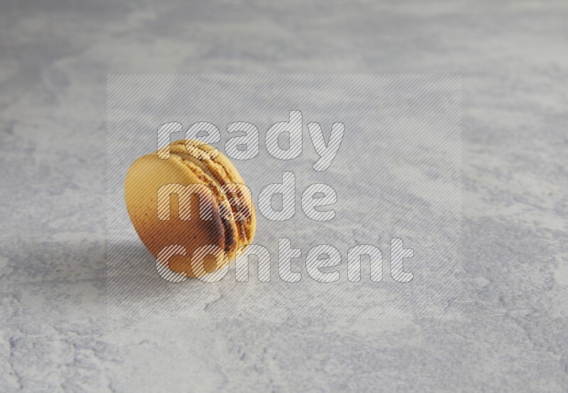 45º Shot of Yellow Crème Brulée macaron on white marble