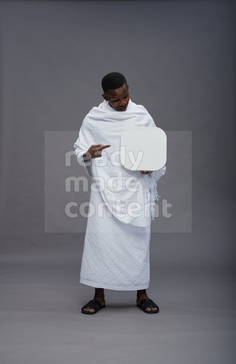 A man wearing Ehram Standing holding social media sign on gray background