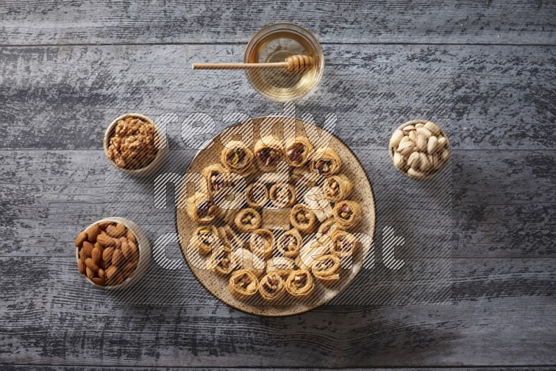 Oriental sweets in a pottery plate with nuts, coffee and honey in a dark setup