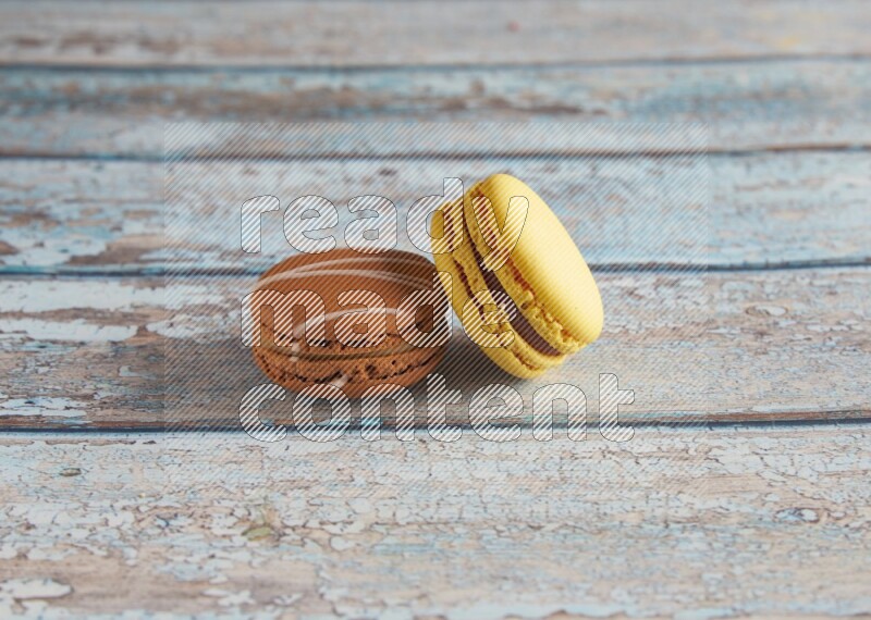 45º Shot of of two assorted Brown Irish Cream, and Yellow Lemon macarons on light blue background