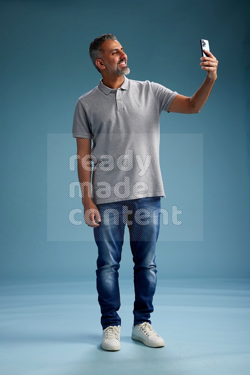 Man Standing taking selfie on blue background