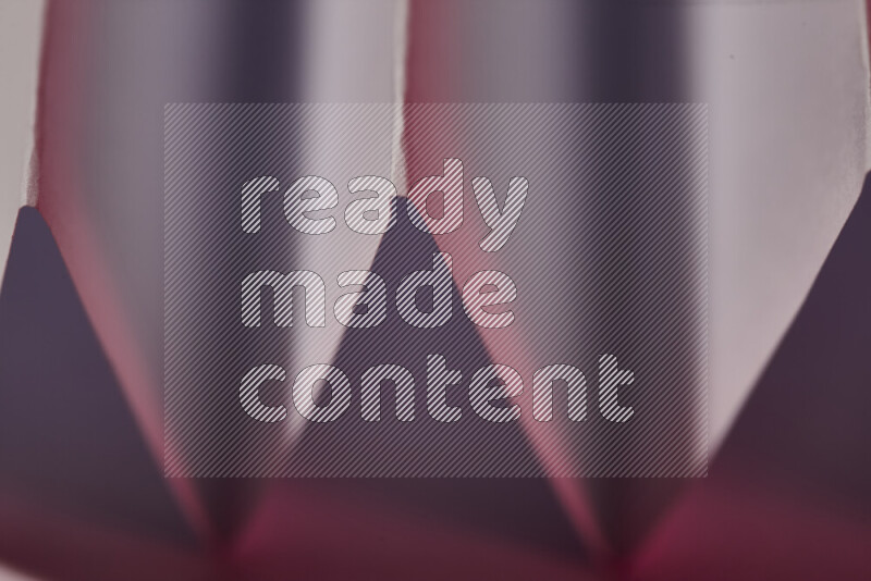 صورة مجردة مقربة تظهر طيات ورقية هندسية حادة بتدرجات اللون الأبيض و الوردي