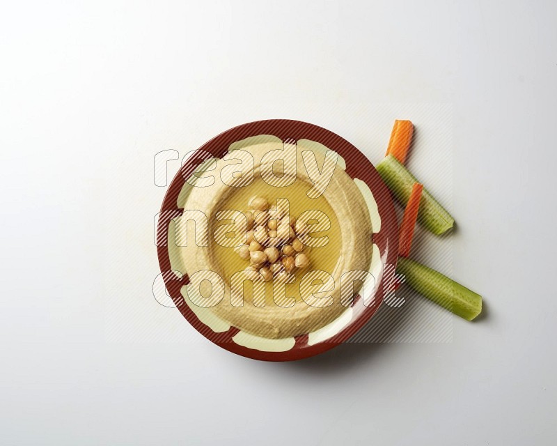 Hummus in a traditional plate garnished with roasted chickpeas  on a white background