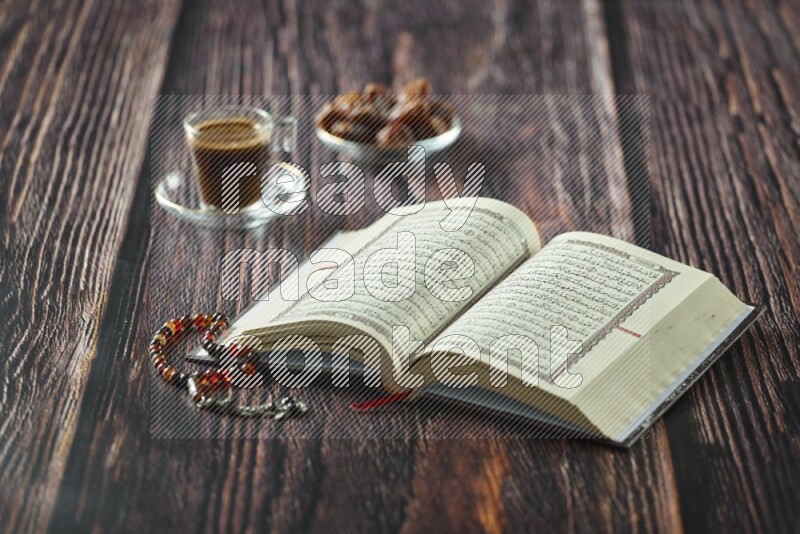 Quran with dates, prayer beads and different drinks all placed on wooden background