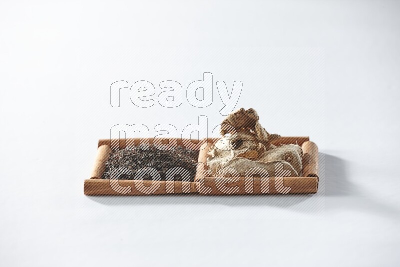 مربعان من أعواد القرفة ممتلئان بالشاي الأسود والزنجبيل المجفف علي خلفية بيضاء