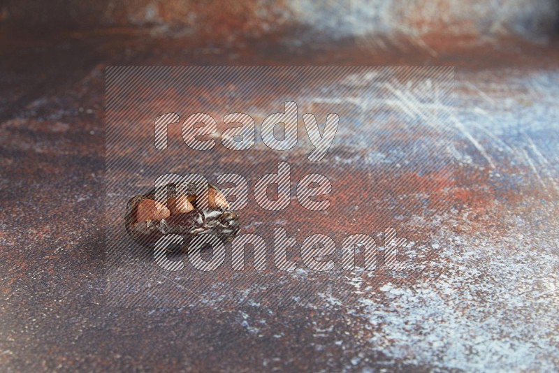 one hazelnut stuffed madjoul date on a rustic reddish background