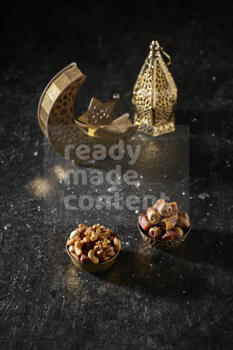 تمر في وعاء معدني مع المكسرات بجانب فوانيس ذهبية علي خلفية سوداء