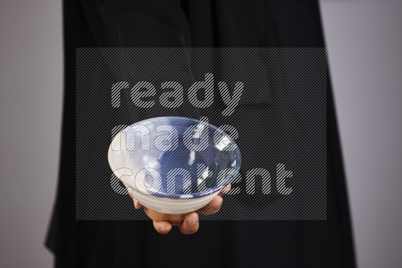 A woman in black abaya holding different pottery essentials in different positions