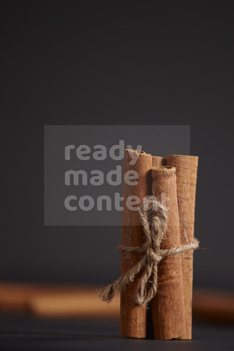 أعواد من القرفة مربوطة مع المزيد من أعواد القرفة علي خلفية سوداء