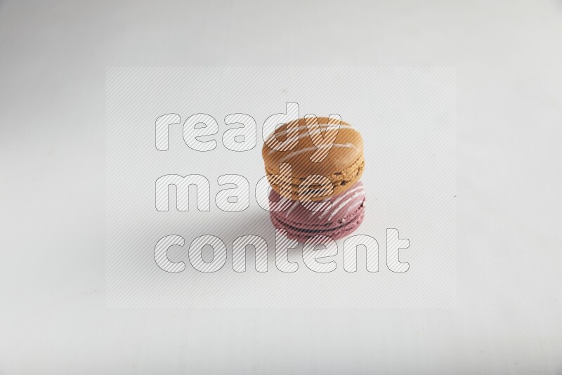 45º Shot of of two assorted Brown Irish Cream, and Red Poppy Flower macarons on white background