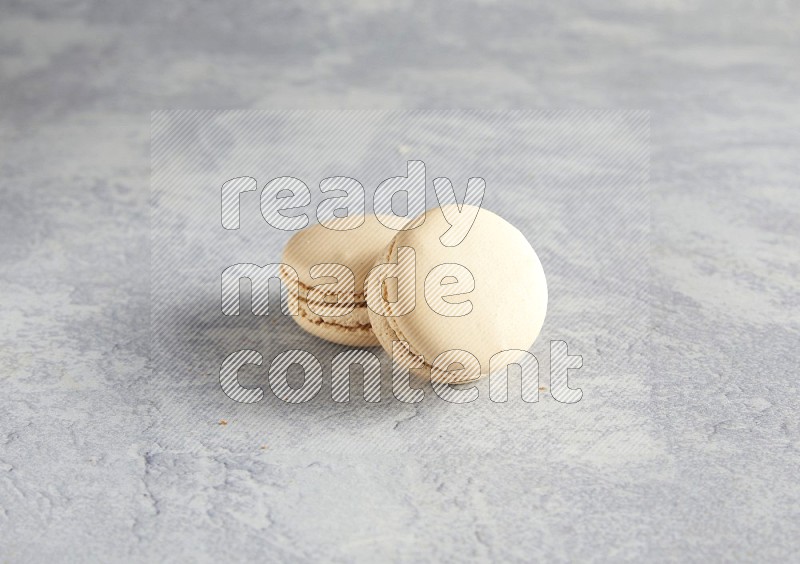 45º Shot of two white marbleCaramel fleur de sel macarons  on white  marble background