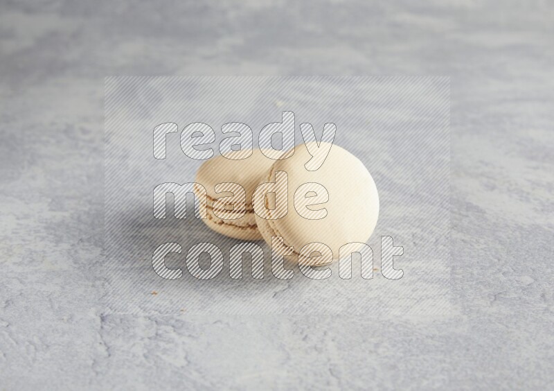 45º Shot of two white marbleCaramel fleur de sel macarons  on white  marble background
