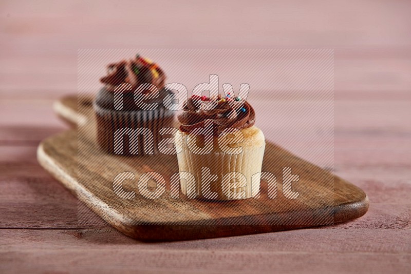 Vanilla mini cupcake topped with chocolate cream on a wooden board