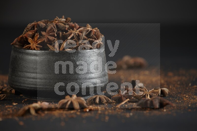 اليانسون النجمي في وعاء أسود مع اليانسون المنثور على خلفية سوداء