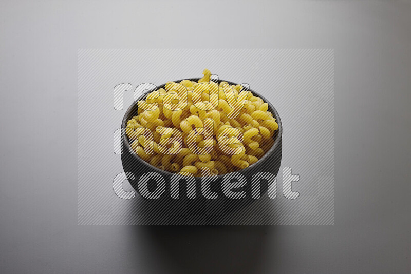 Twist pasta in a pottery bowl on grey background