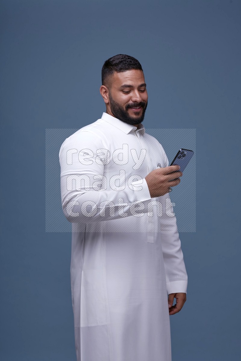 A man Texting on Blue Background wearing Saudi Thob