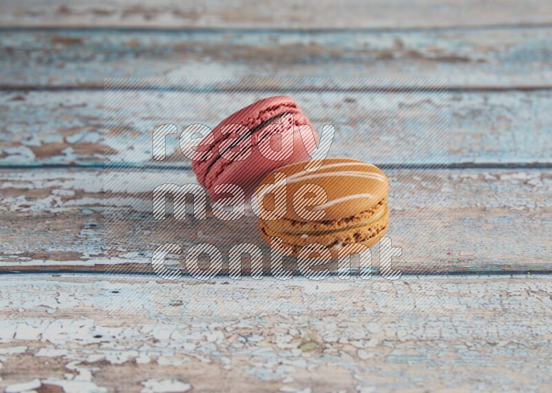 45º Shot of of two assorted Brown Irish Cream, and Pink Raspberry macarons on light blue background