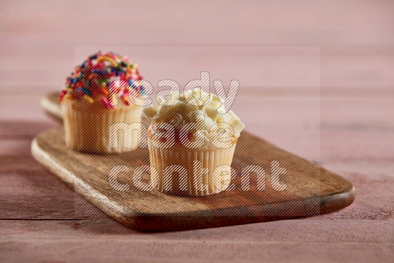 Vanilla mini cupcake topped with white chocolate curls on a wooden board