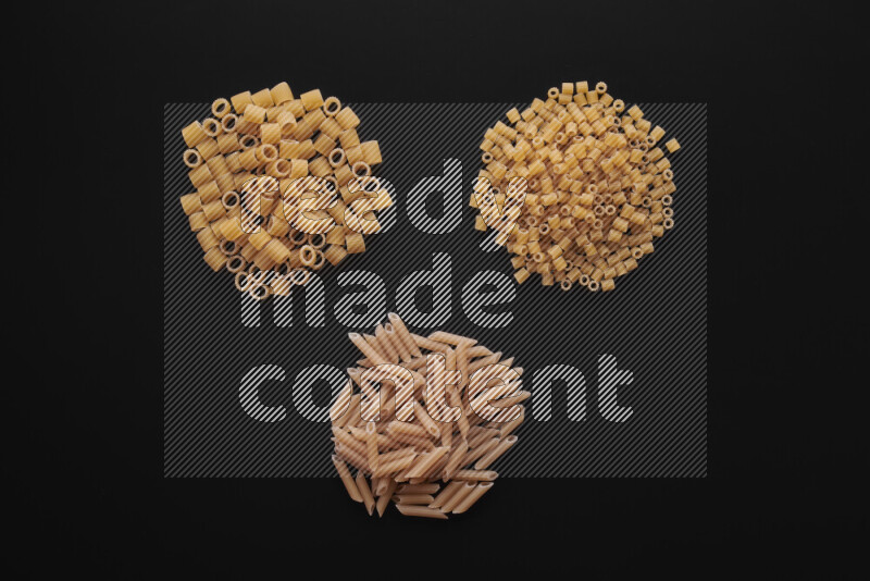 Different pasta types in bunches on black background