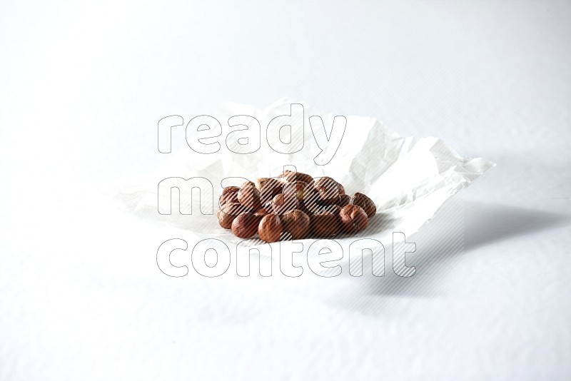 Peeled hazelnuts on a crumpled piece of paper on a white background in different angles