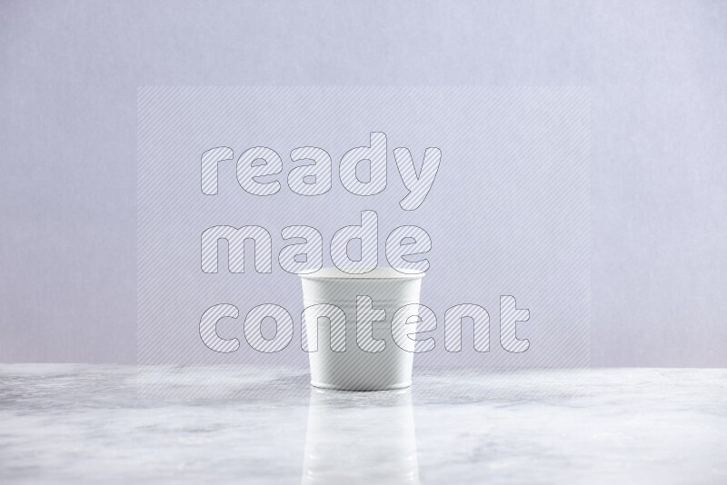 An empty white plant pot on grey marble background
